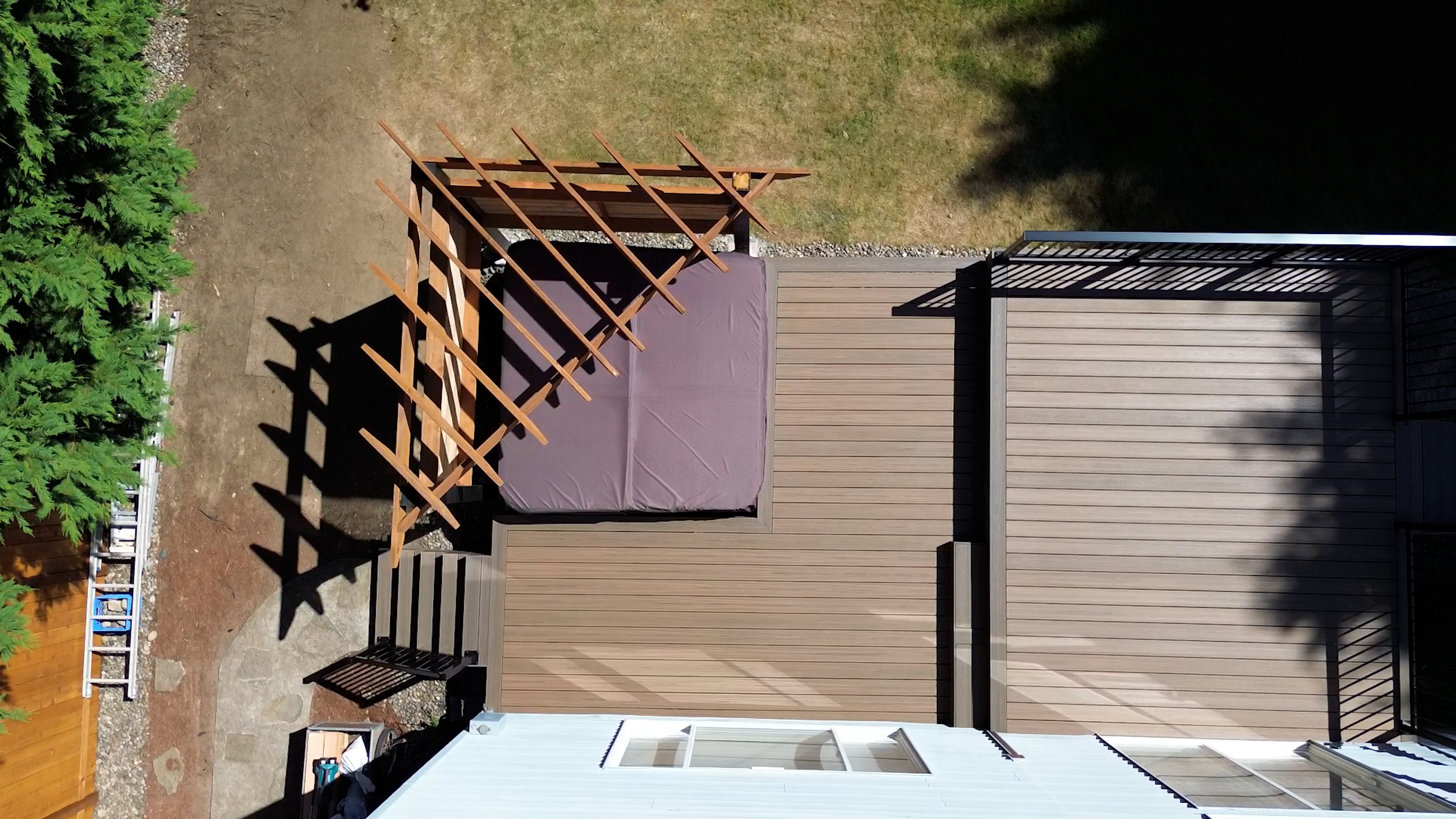 Wide view of deck with black aluminum picket railings and hot tub pergola